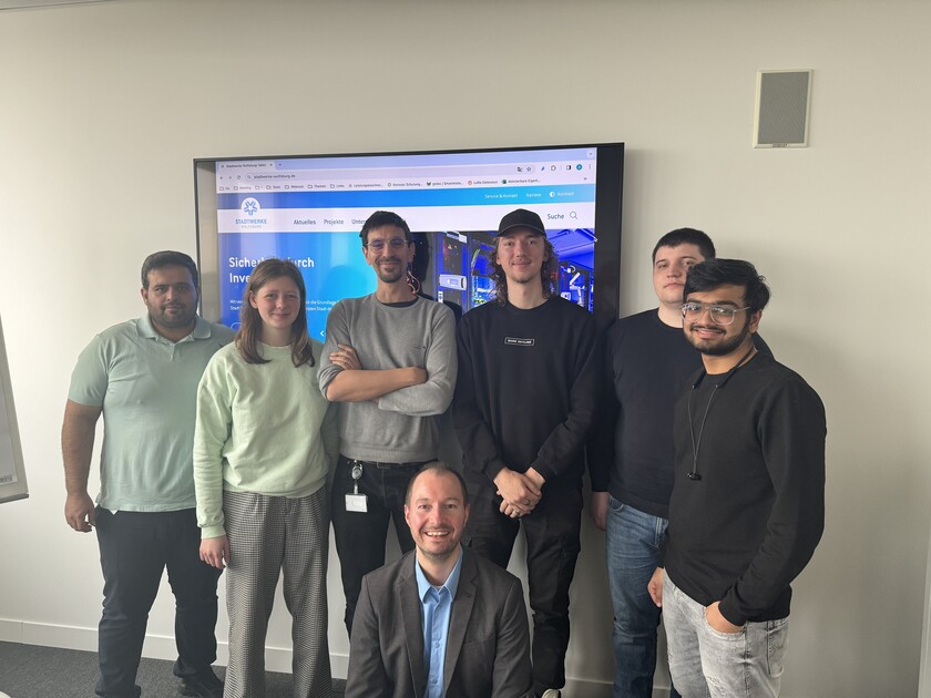 20240417_Digitalisierungsprojekt_Team im WNT Das Team des Digitalisierungsprojektes im WNT vor einer Wand und einem Bildschirm mit der Website der Stadtwerke Wolfsburg