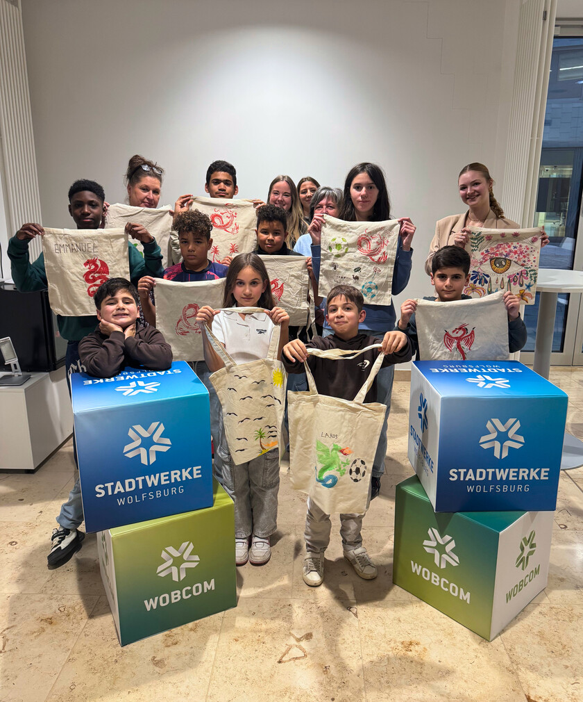 Alle Kinder vom Bastel- und Spielenachmittag halten ihre selbst angemalten Beutel in die Kamera.